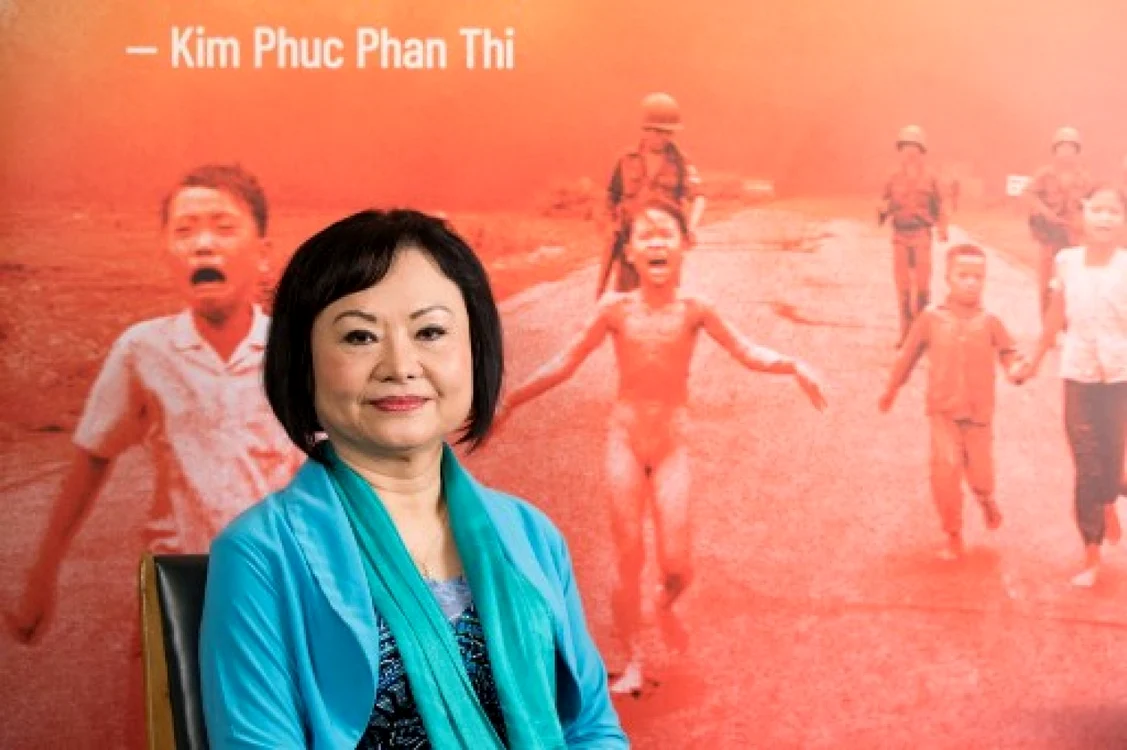 Phan Thi Kim Phuc, în 2022, în faţa fotografiei celebre care o arată fugind îngrozită după ce a fost arsă de napalm, în timpul războiului din Vietnam FOTO: GEOFFROY VAN DER HASSELT / AFP