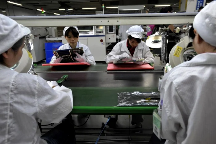 Muncitori chinezi asamblează componente electronice FOTO AFP