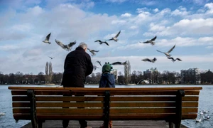 Un bărbat şi un copilaş hrănesc pescăruşii de pe malul unui lac artificial din Hanovra Germania FOTO EPA / Peter Steffen