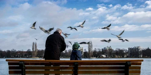 Un bărbat şi un copilaş hrănesc pescăruşii de pe malul unui lac artificial din Hanovra Germania FOTO EPA / Peter Steffen