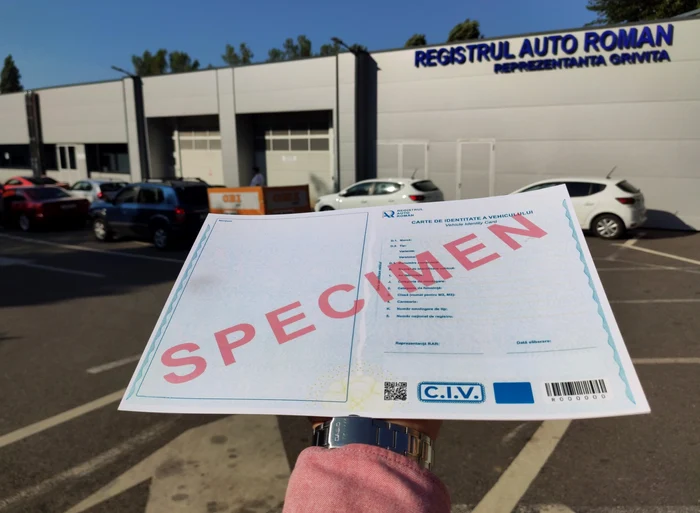 Cineva arată cartea de identitate a mașinii în fața sediului RAR