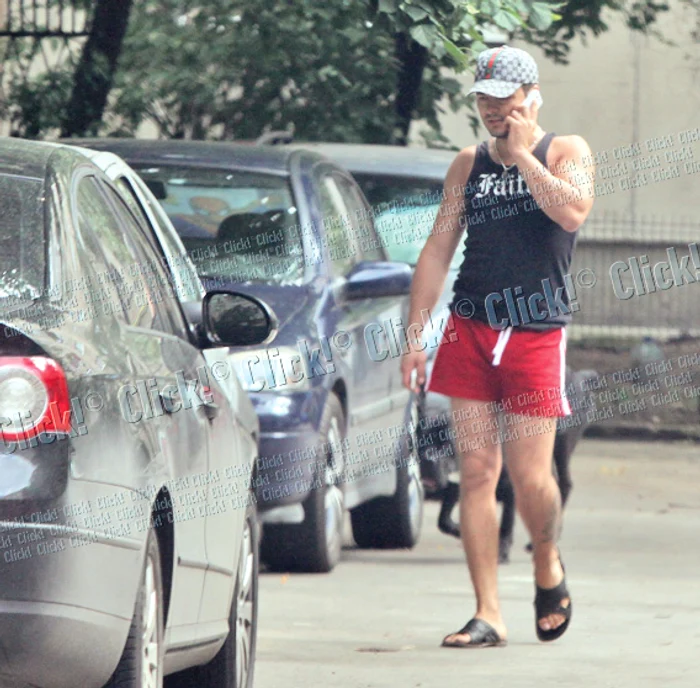 Iese din bloc în şort,  vorbind la mobil