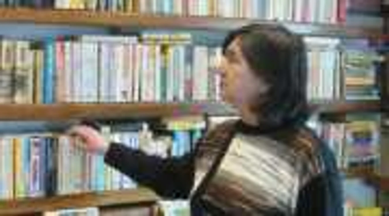 O bibliotecară priveşte melancolică cărţile de împrumut