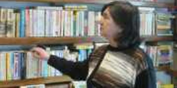 O bibliotecară priveşte melancolică cărţile de împrumut