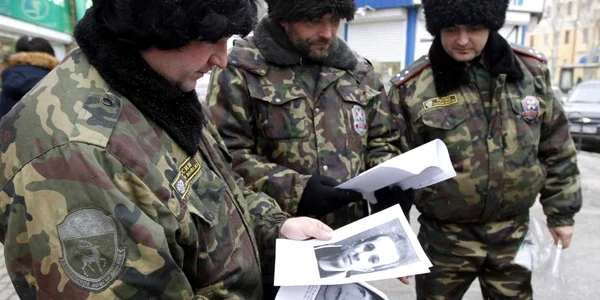 Cazacii ruşi se uită la portrete de persoane suspecte implicate în acte terorism