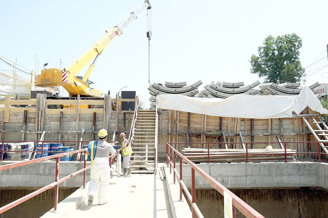 Înconjuraţi de betoane,  muncitorii se răcoresc  la umbra materialelor  de construcţie