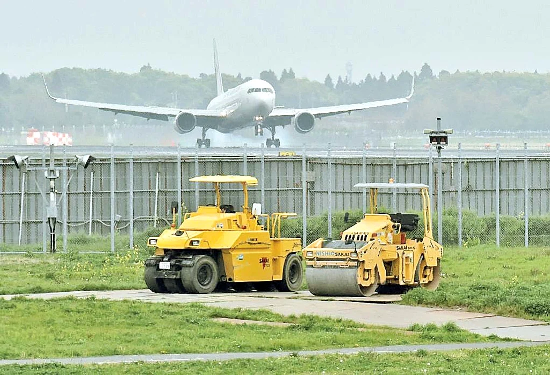 În curte - utilajele de agricultură, dincolo de gard - avioanele cu pasageri