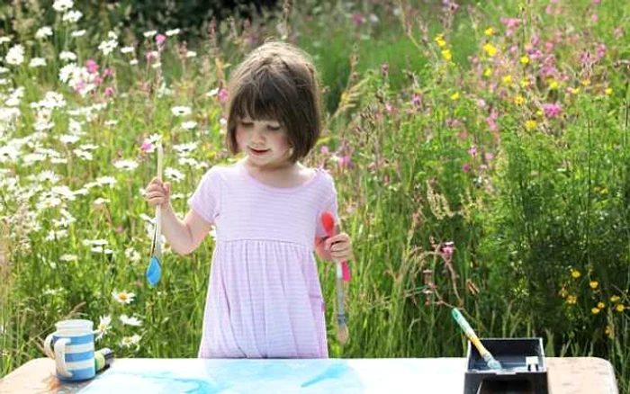 Fetiţa pictează întotdeauna cu o linguriţă de plastic în mâna stângă