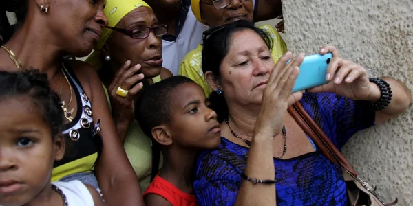 Cubanezi uitandu-se la un telefon mobil FOTO EPA