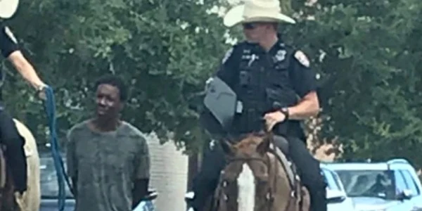 Afroamericanul Donlad Neely escortat legat de o funie de catre doi politisti calare FOTO Twitter