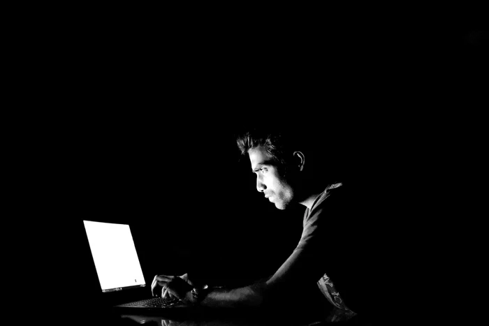 Un hacker se uită în ecranul laptopului