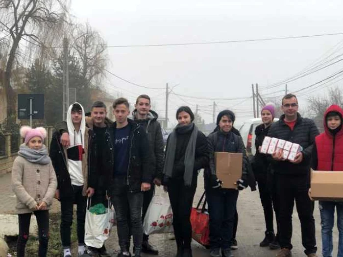 Profesorul Vasile Postolachi( al doilea din dreapta) alături de elevi dăruind ajutoare sătenilor nevoiaşi FOTO Cosmin Zamfirache