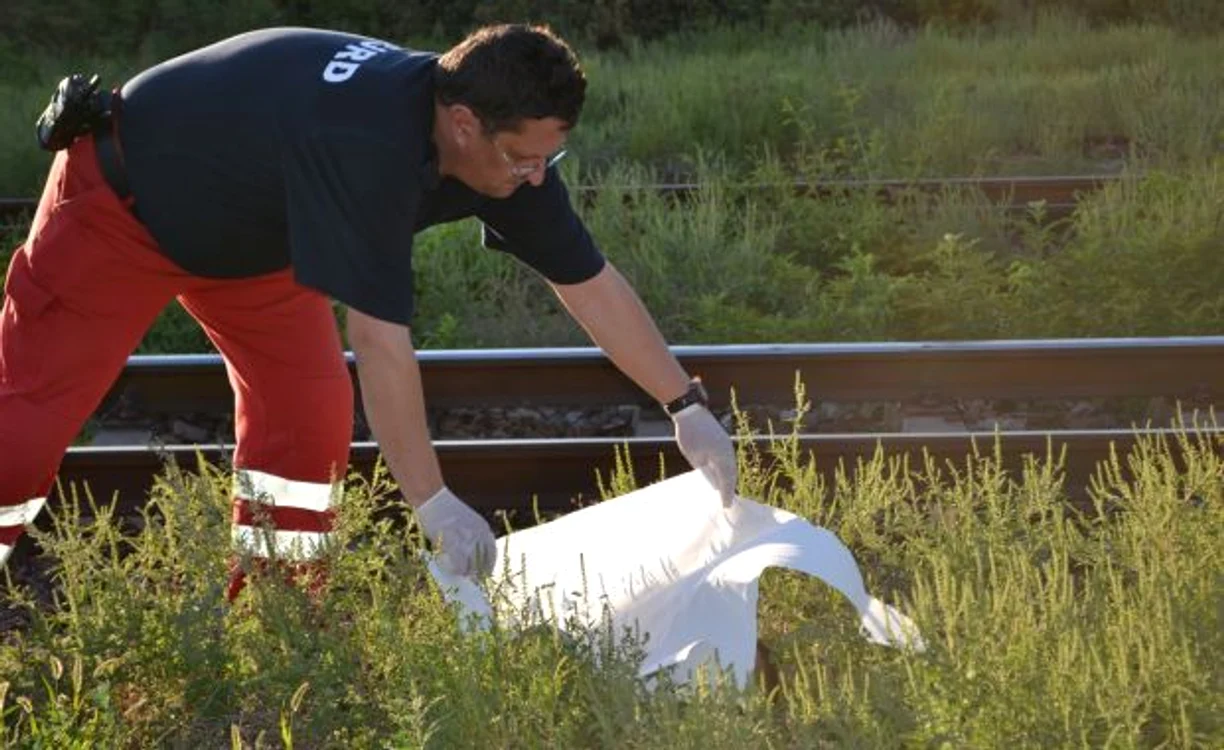 
    Unul dintre membrii echipajului SMURD acoperind capul victimei (Foto: Marius Mototolea)  