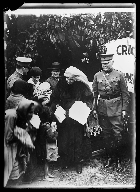 Regina Maria distribuie haine trimise de Crucea Roșie Americană, însoțită de col. Anderson (© LoC)