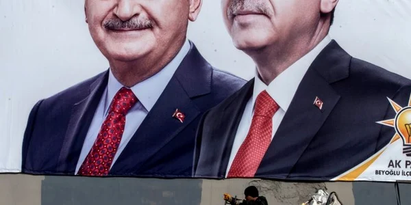 Un bărbat care adună hârtie pentru reciclat trece prin faţa unui poster pe care apare preşedintele turc Recep Tayyip Erdogan şi candidatul la primăria Istanbulului din partea partidului pentru Justiţie şi Dezvoltare (AK) Binali Yildirim în Istanbul T