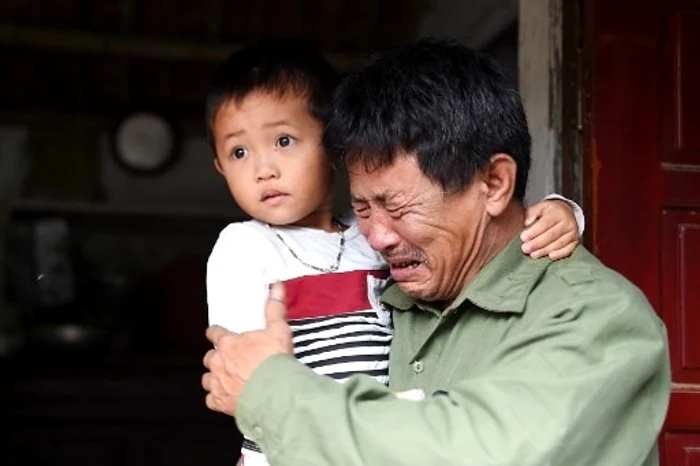 
    Tatăl unei posibile victime din camionul din Essex unde au fost găsiți 39 de imigranți morți, plângând de disperare cu nepoțelul în brațe Foto: AFP  