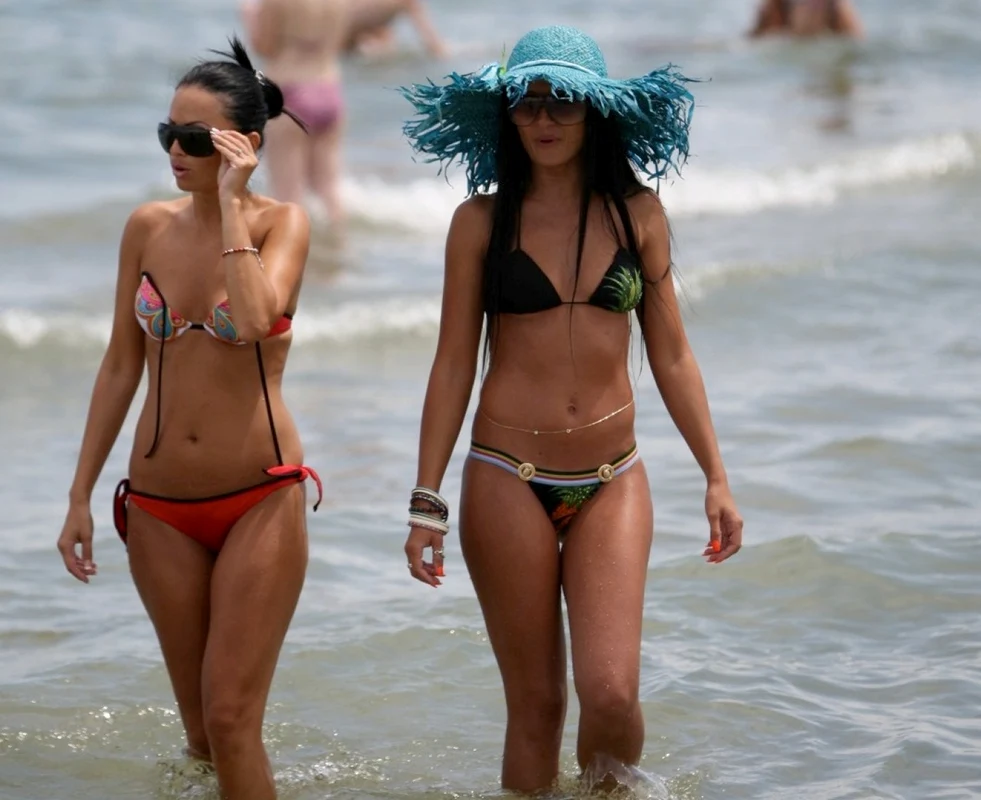 Fete în costum de baie în mare pe plajă pe litoral