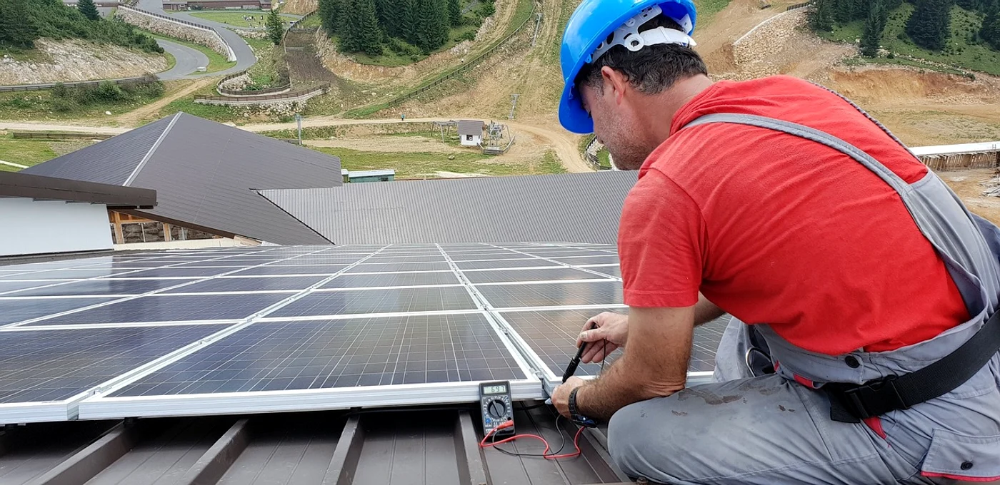 Un instalator montează panouri fotovoltaice pe un acoperiș