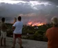 Oamenii se uită la un foc sălbatic izbucnit în Rafina în apropiere de Atena Grecia Cel puţin 50 de persoane au murit şi mai multe au fost rănite deoarece focul s a extins în zonele din jurul Atenei din cauza rafalelor puternice ale vîntului FOTO AFP