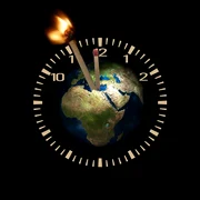Globul pământesc în centrul unui ceas cu chibrituri drept pendule, unul dintre el fiind aprins   pixabay jpg
