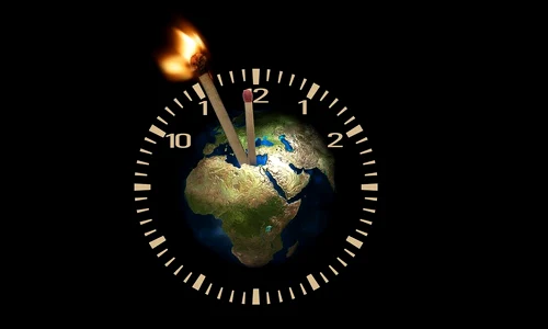 Globul pământesc în centrul unui ceas cu chibrituri drept pendule, unul dintre el fiind aprins pixabay jpg