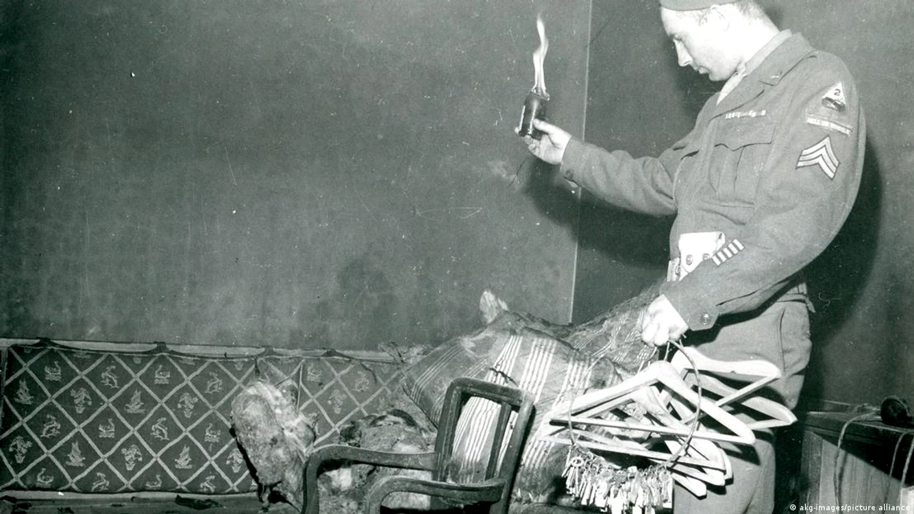 Un soldat asigurând-şi o "bucată" de suvenir din canapeaua pe care a fost găsit trupul lui Hitler 