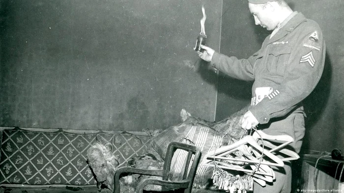 Un soldat asigurând-şi o "bucată" de suvenir din canapeaua pe care a fost găsit trupul lui Hitler
