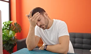 young hispanic man suffering headache sitting table dinning room jpg