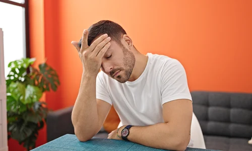 young hispanic man suffering headache sitting table dinning room jpg