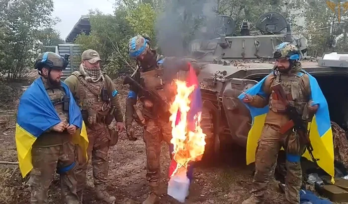 Soldați ucraineni care au eliberat orașe de sub ruși ard un steag rusesc FOTO Profimedia