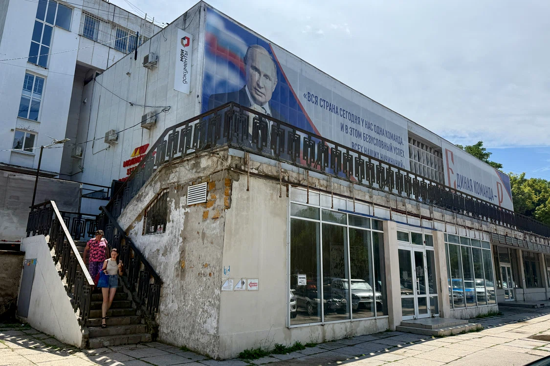 Oameni trec pe lângă un panou cu portretul lui Putin, în Sevastopol, Crimeea 