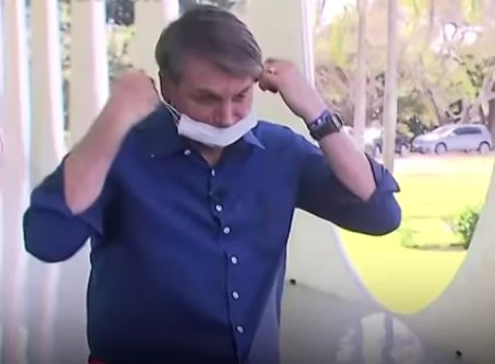 Jair Bolsonaro dându-şi masca jos pentru a le arăta jurnaliştilor că se simte bine Captură YouTube/ The Guardian