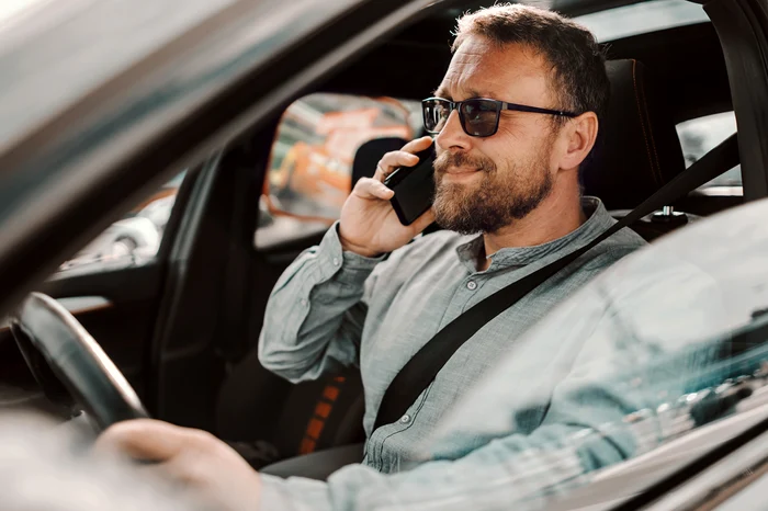 bărbat în mașină vorbește la telefon