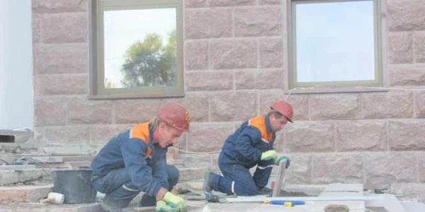 Alţi muncitori pun plăci de granit pe pragul clădirii