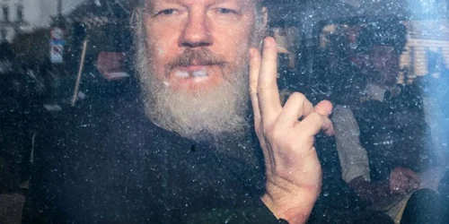 Julian Assange gesticulează către fotoreporteri dintr-un vehicul al poliţiei la sosirea sa la curtea Magistraţilor din Westminster în Londra Marea Britanie FOTO Guliver / Getty Images / Jack Taylor