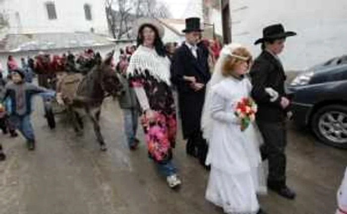 Sătenii adunaţi la porţile caselor cinstesc alaiul cu gogoşi şi sume de bani