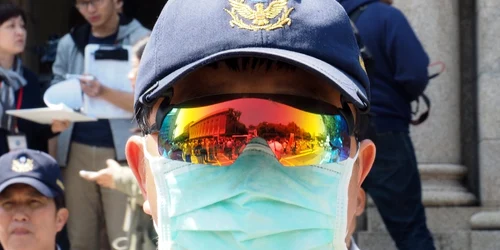 Participanţi la miting se reflectă în ochelarii unui politist care păzeşte clădirea Curţii Constituţionale unde se dezbate legalizarea căsătoriilor între persoane de acelaşi sex în Taipei Taiwan FOTO EPA David Chang