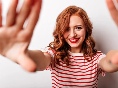 playful ginger girl posing with pleasure white wall stunning caucasian woman striped t shirt smiling jpg