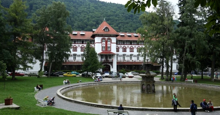 Hotel într-o zonă de munte cu o fântână arteziană în față