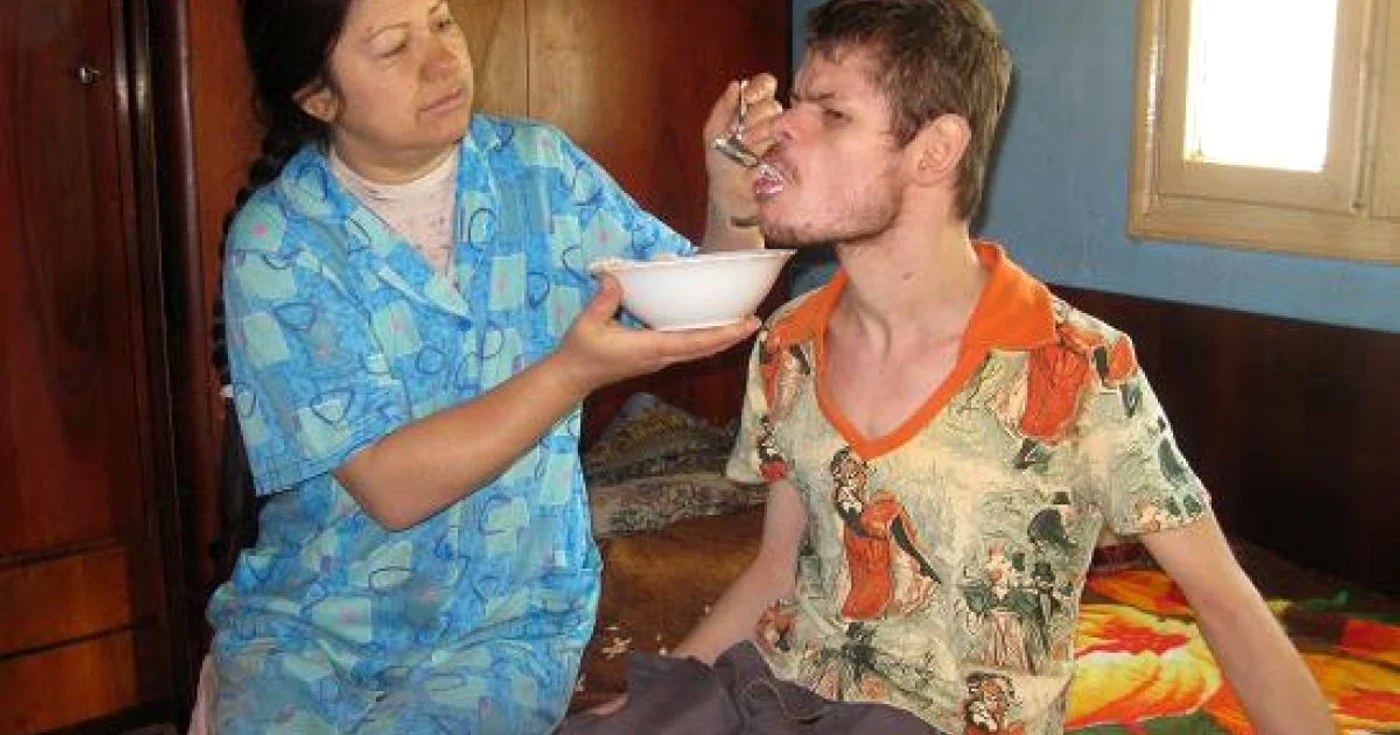 Femeia îşi hrăneşte copilul de 25 de ani cu linguriţa