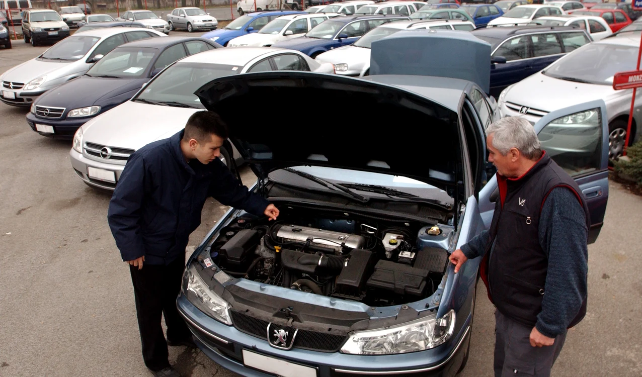 Doi bărbați se uită la motorul unei mașini second hand