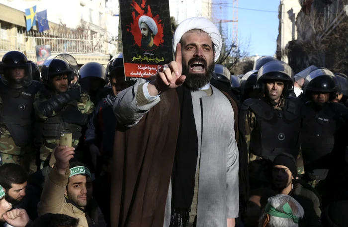 Înconjurat de poliție, un cleric musulman se adresează mulțimii în fața ambasadei Arabiei Saudite de la Teheran, în timpul unei demonstrații ce a urmat execuției clericului șiit Nimr al-NimrSursă: AP