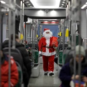 Manipulantul de tramvai (vatman) STB Gorgonea Mitică din cadrul depoului Militari, îmbrăcat în Moș Crăciun, împarte bomboane copiilor în timpul turei pe tramvaiul 10, în București. FOTO Inquam Photos / Octav Ganea