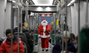 Manipulantul de tramvai (vatman) STB Gorgonea Mitică din cadrul depoului Militari, îmbrăcat în Moș Crăciun, împarte bomboane copiilor în timpul turei pe tramvaiul 10, în București. FOTO Inquam Photos / Octav Ganea