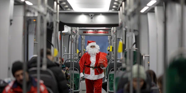Manipulantul de tramvai (vatman) STB Gorgonea Mitică din cadrul depoului Militari, îmbrăcat în Moș Crăciun, împarte bomboane copiilor în timpul turei pe tramvaiul 10, în București. FOTO Inquam Photos / Octav Ganea
