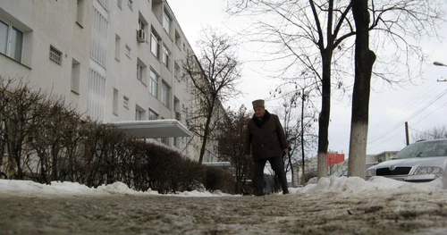 Un pieton în vârstă se deplasează cu greu pe trotuarele din Iaşi