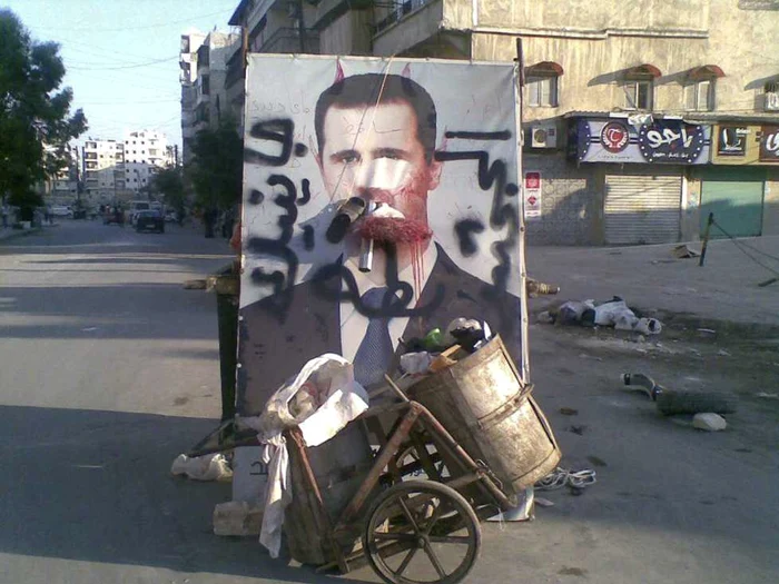 Poster distrus cu imaginea liderului sirian Bashar al-Assad, lângă un coş de gunoi în oraşul Alep FOTO: Reuters