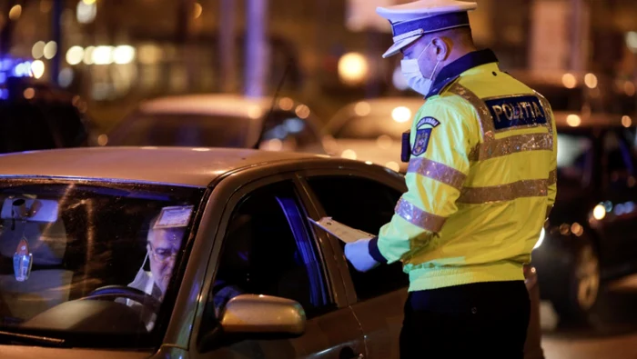 Un poliţist verifică documentele unui şofer în perioada restricţiilor de circulaţie pe timpul nopţii. Foto: InquamPhotos / George Călin