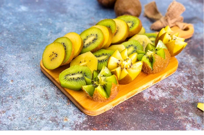 Un tocător plin cu kiwi galben și kiwi verde