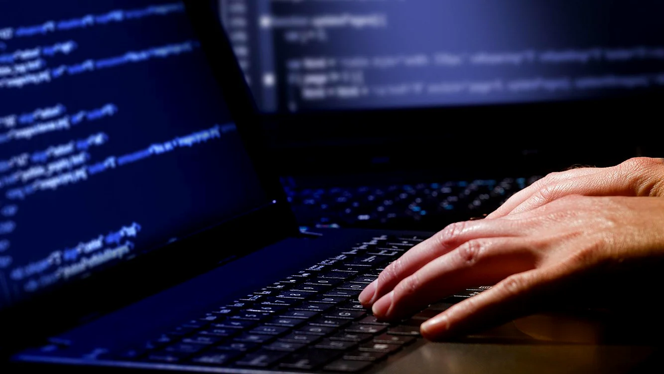 Un hacker tastează informațiile pe un laptop